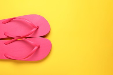 Photo of Stylish pink flip flops on yellow background, top view. Space for text