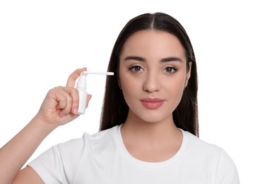 Young woman using ear spray on white background