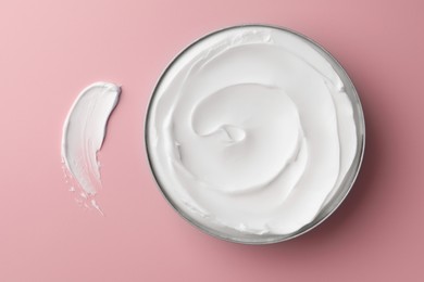 Jar of face cream and sample on pink background, flat lay