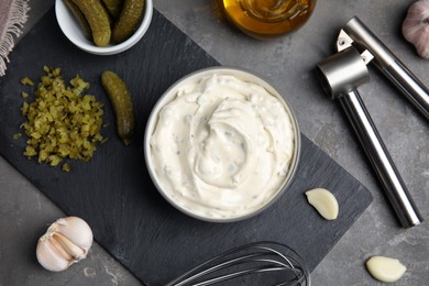 Photo of Tasty tartar sauce and ingredients on grey table, flat lay