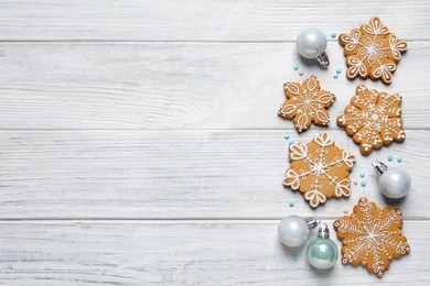 Photo of Tasty Christmas cookies and baubles on white wooden table, flat lay. Space for text