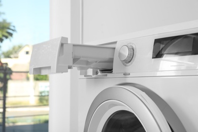 Photo of Washing machine with open detergent drawer in laundry room, closeup