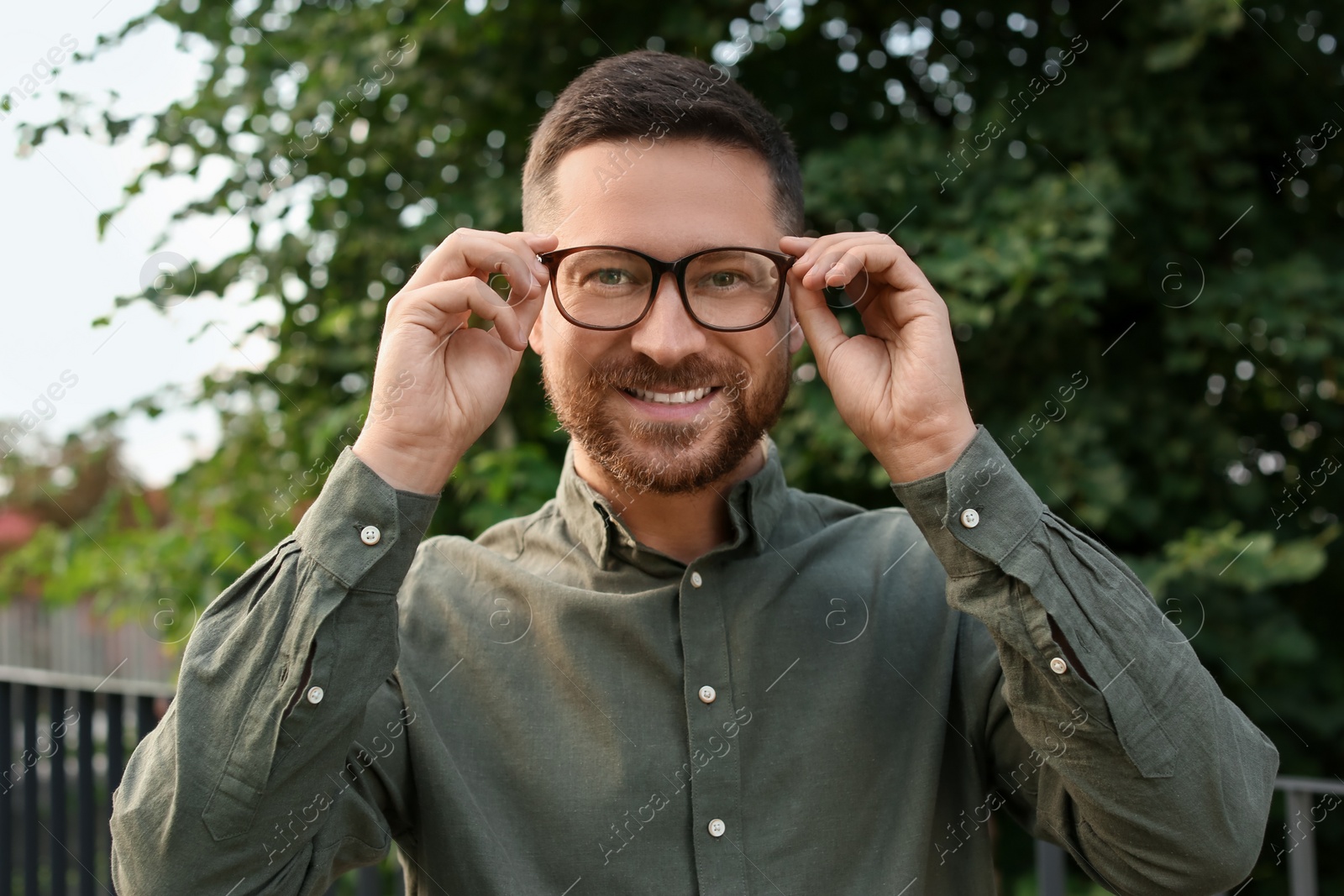 Photo of Portrait of handsome bearded man in glasses outdoors