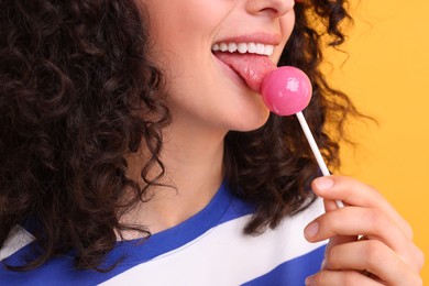 Woman with lollipop on yellow background, closeup