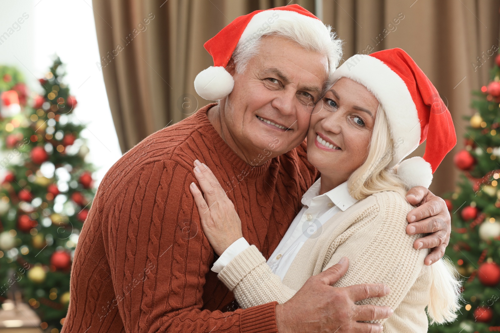 Photo of Happy mature couple in Santa hats at home. Christmas celebration