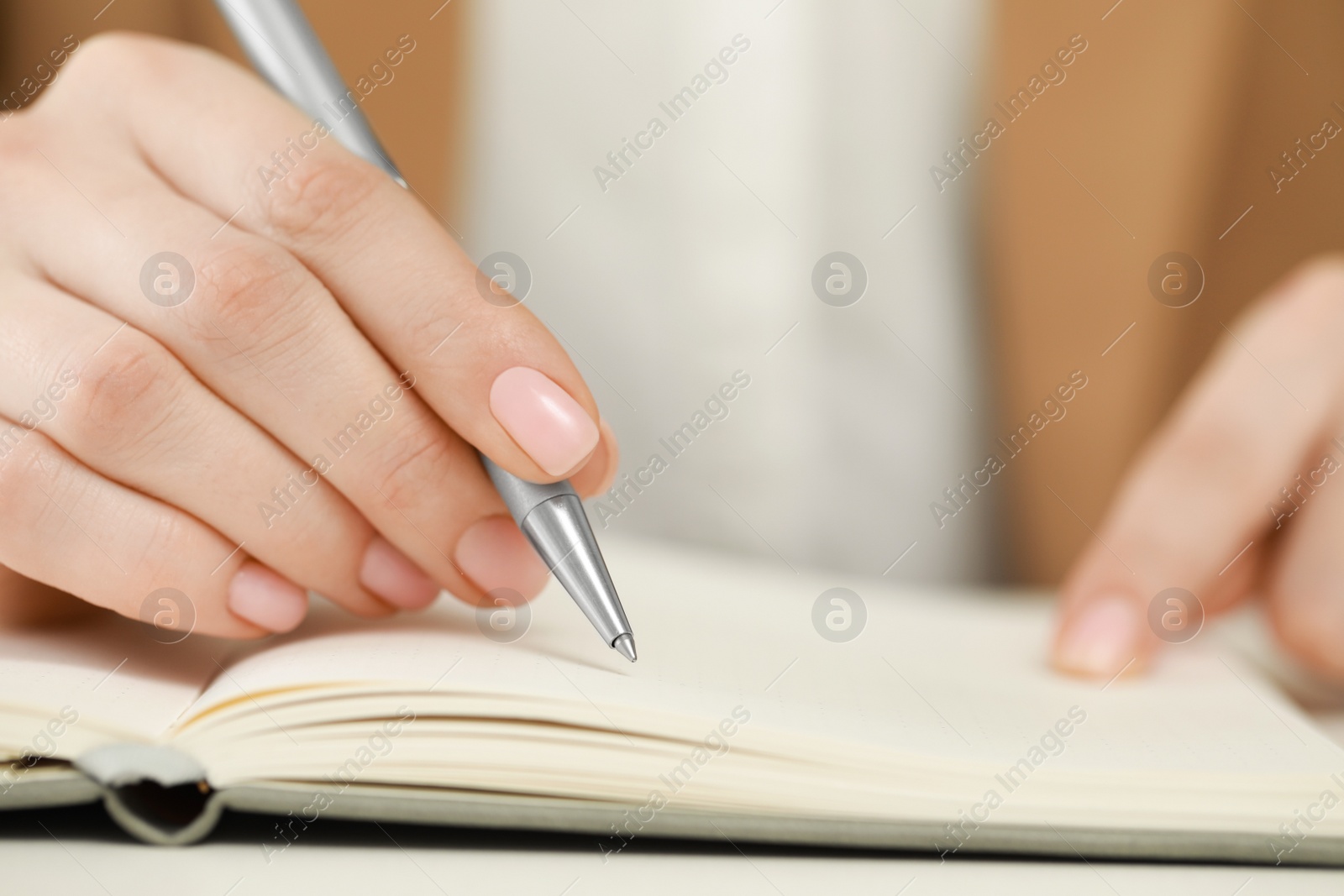 Photo of Woman writing in notebook at white table, closeup