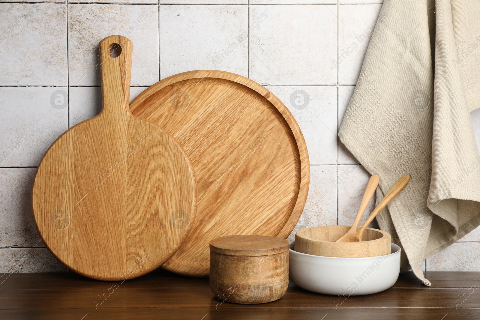 Photo of Wooden cutting boards and dishware on table near tiled wall