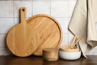 Photo of Wooden cutting boards and dishware on table near tiled wall