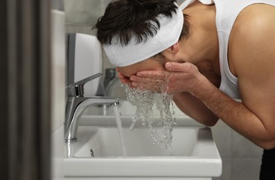 Photo of Man with headband washing his face in bathroom