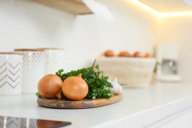 Fresh onions and parsley on white countertop in modern kitchen