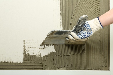 Closeup of worker spreading concrete on wall with spatula, space for text. Tile installation