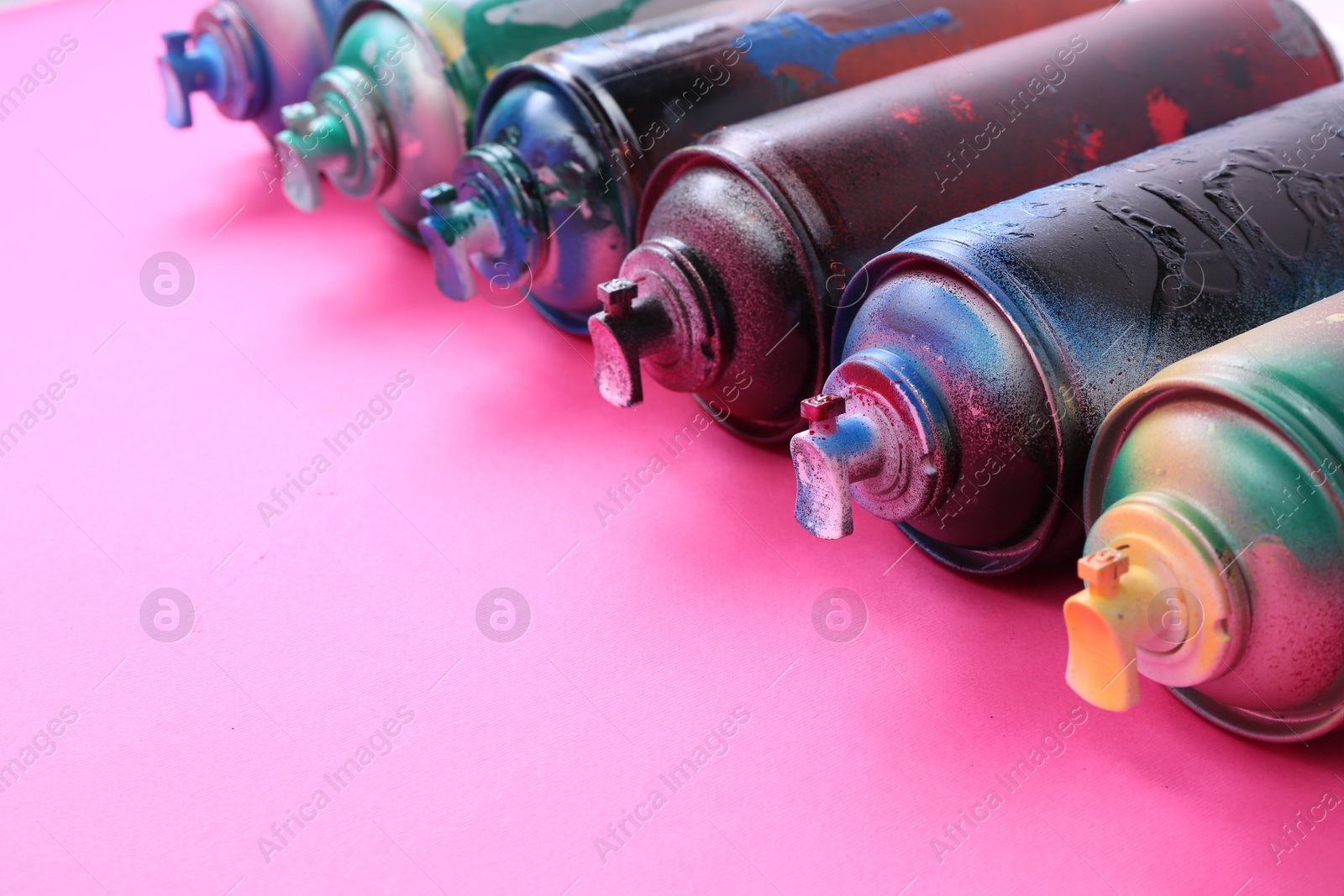 Photo of Many spray paint cans on pink background, closeup. Space for text