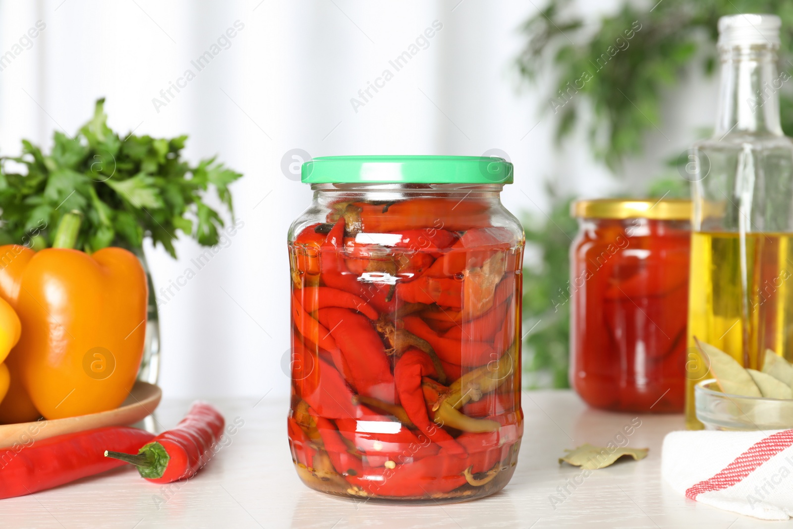 Photo of Glass jar of pickled pickled peppers on white table