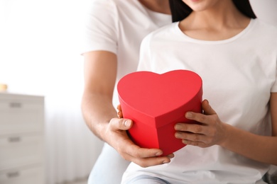 Photo of Man presenting gift to his beloved woman at home, closeup. Valentine's day celebration