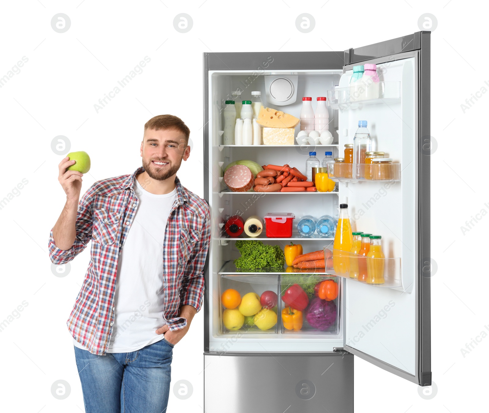 Photo of Young man with apple near open refrigerator on white background