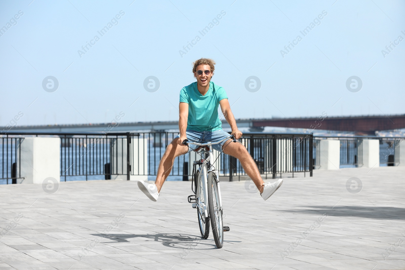 Photo of Handsome young man riding bicycle outdoors on sunny day