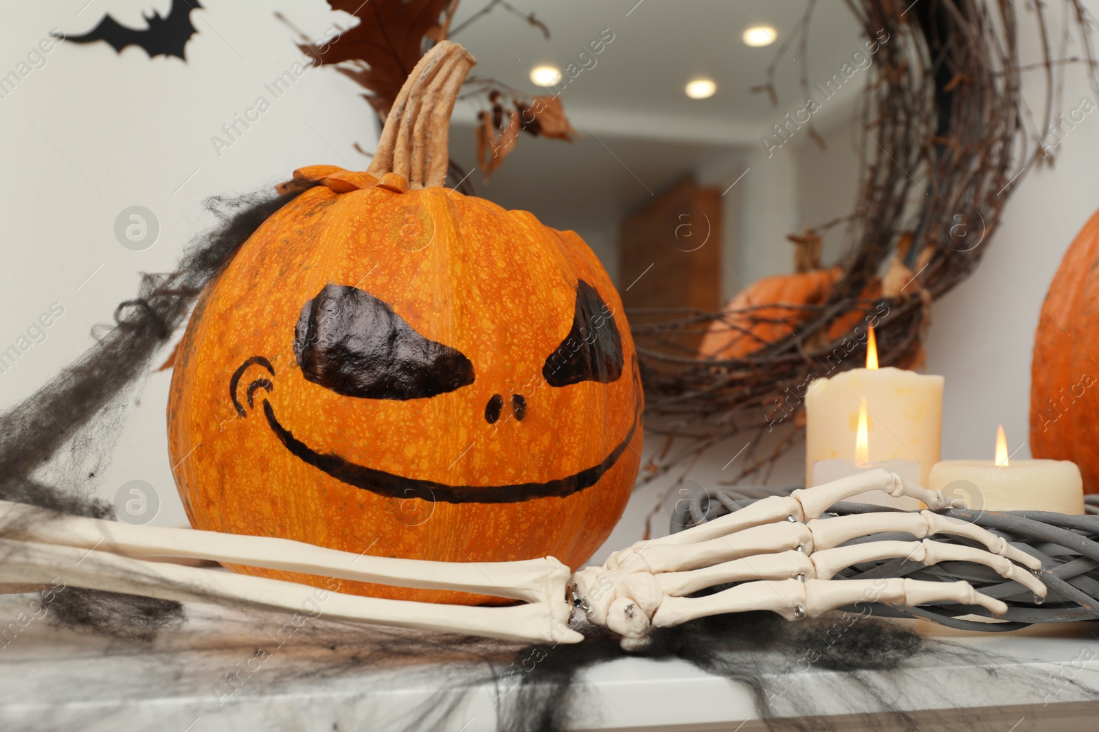 Photo of Pumpkin with drawn spooky face and candles on table. Halloween decor