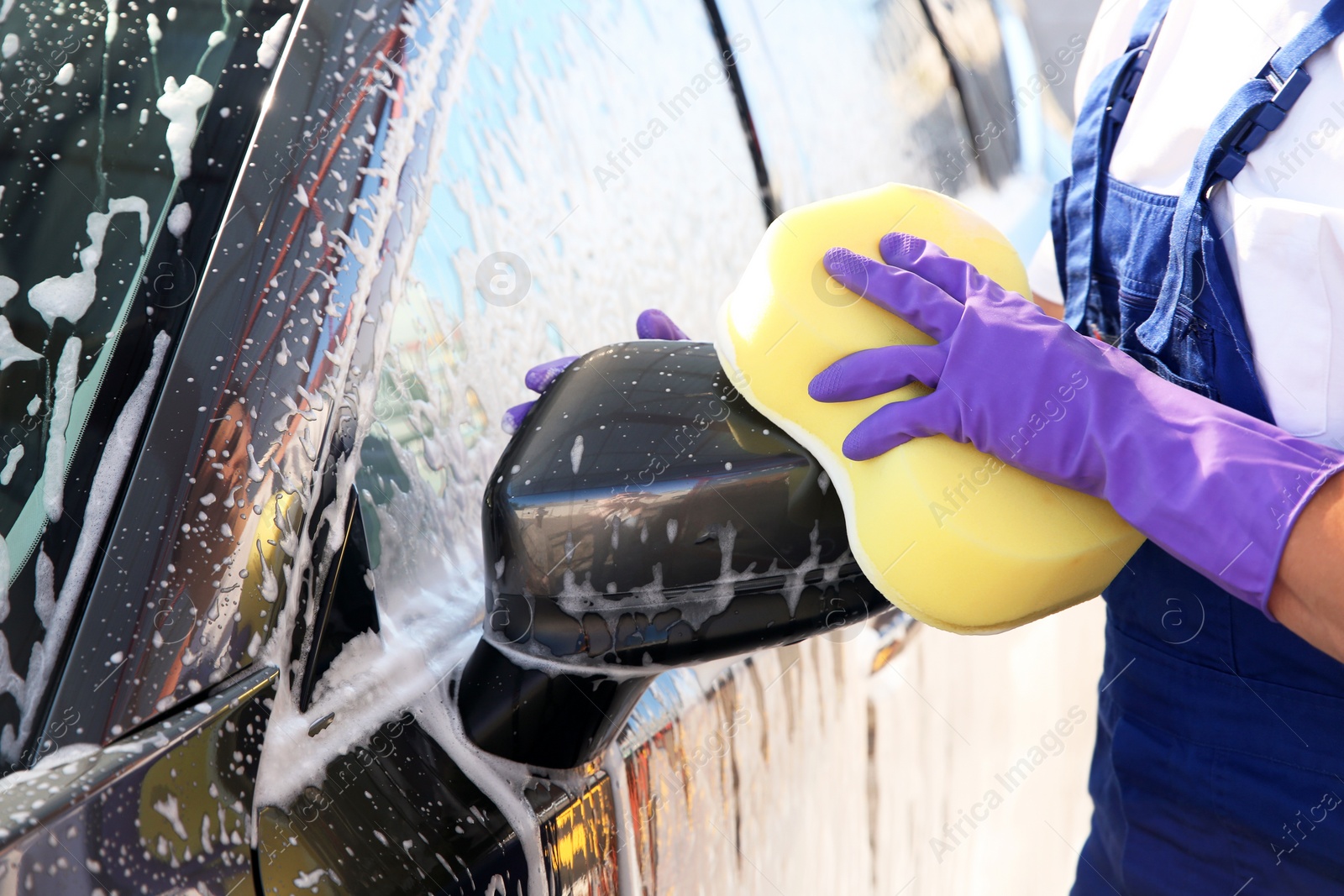 Photo of Man washing car with sponge outdoors, closeup