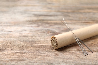 Photo of Moxa stick with needles for acupuncture on wooden table