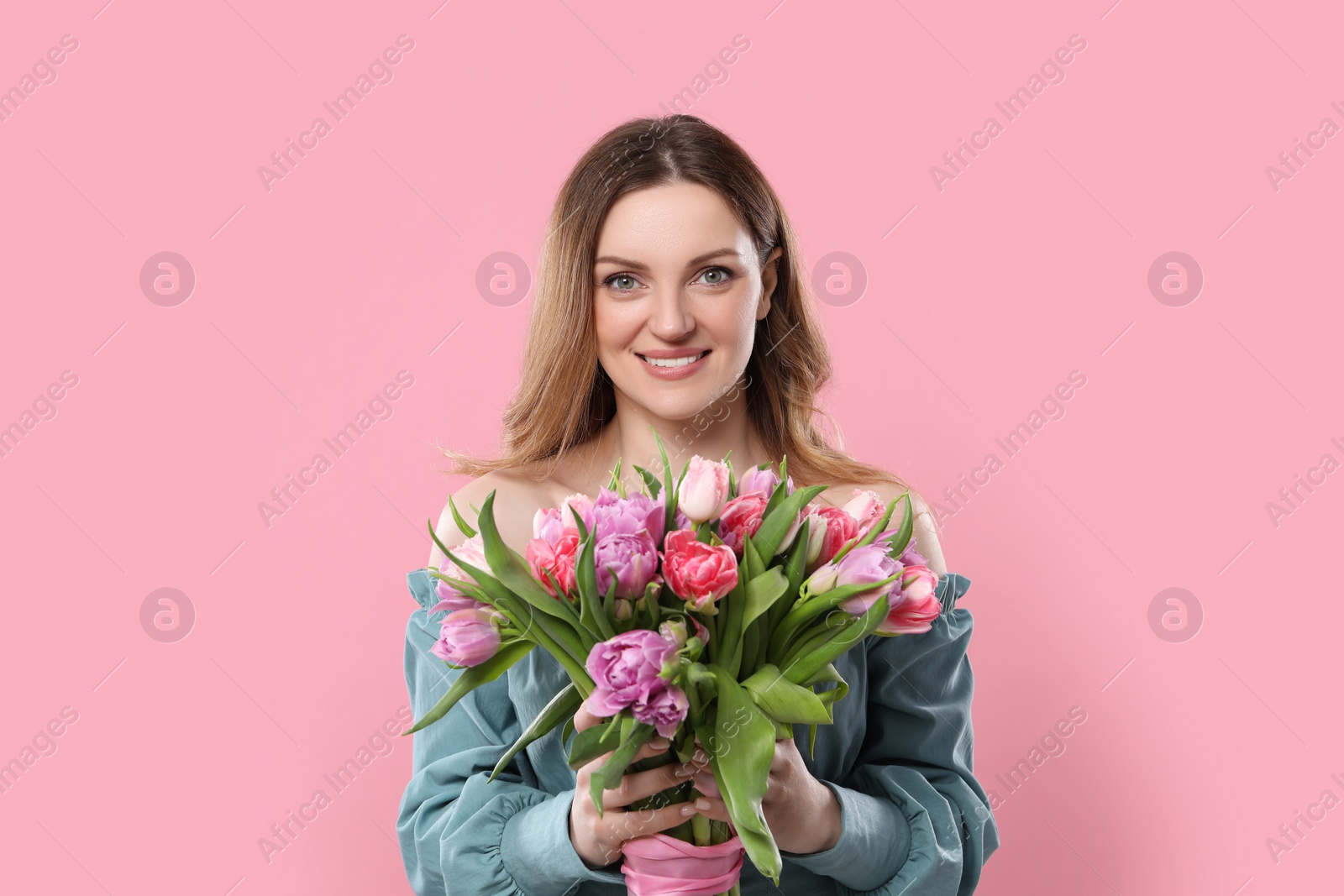 Photo of Happy young woman with bouquet of beautiful tulips on pink background