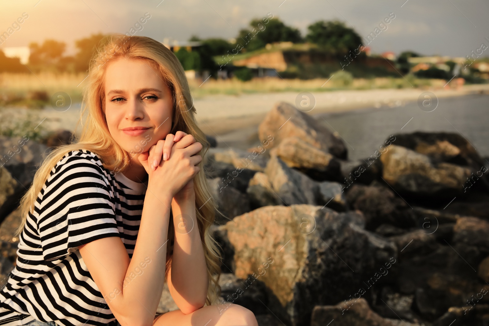 Photo of Beautiful young woman on rocky sea beach, space for text