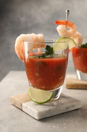 Photo of Tasty shrimp cocktail with sauce in glasses and lime on light grey table, closeup