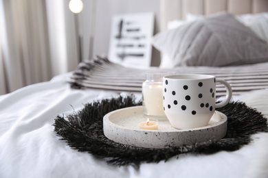 Photo of Cup of drink and burning candles on bed in room, space for text. Interior design
