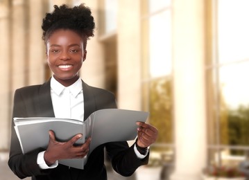 Lawyer, consultant, business owner. Confident woman with file folders smiling outdoors, space for text