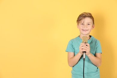 Cute boy with microphone on color background. Space for text