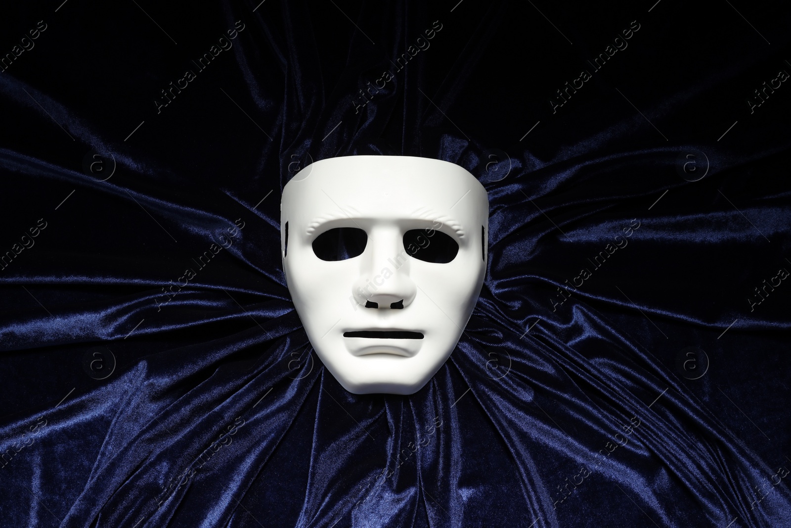 Photo of Theater arts. White mask on blue fabric, top view