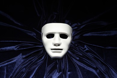 Theater arts. White mask on blue fabric, top view