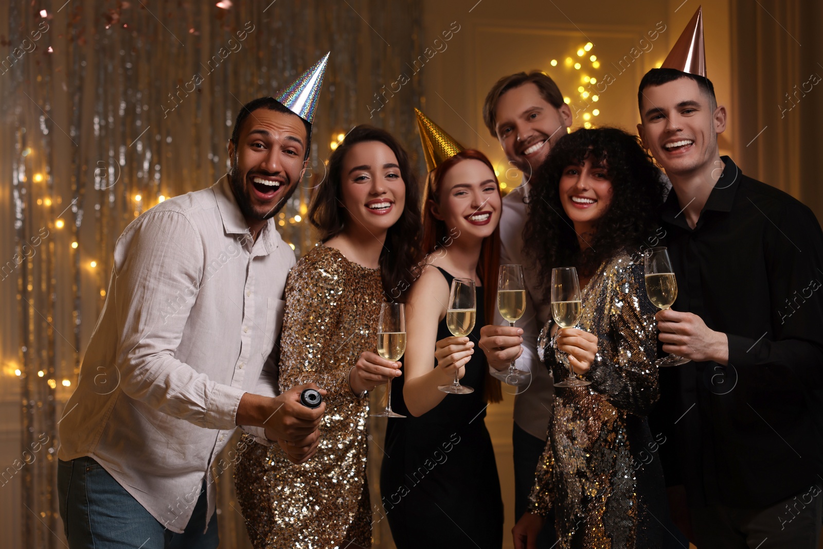 Photo of Happy friends with glasses of sparkling wine celebrating birthday indoors