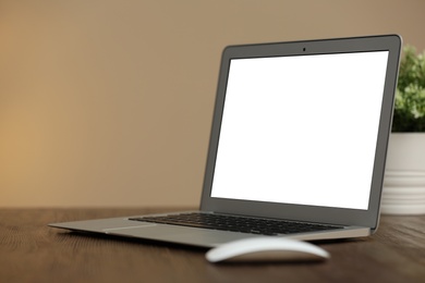 Laptop with blank screen on table indoors. Space for text