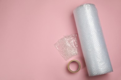 Photo of Bubble wrap and tape on light pink background, flat lay. Space for text