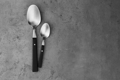 Photo of Clean empty table spoons on grey background, top view. Space for text