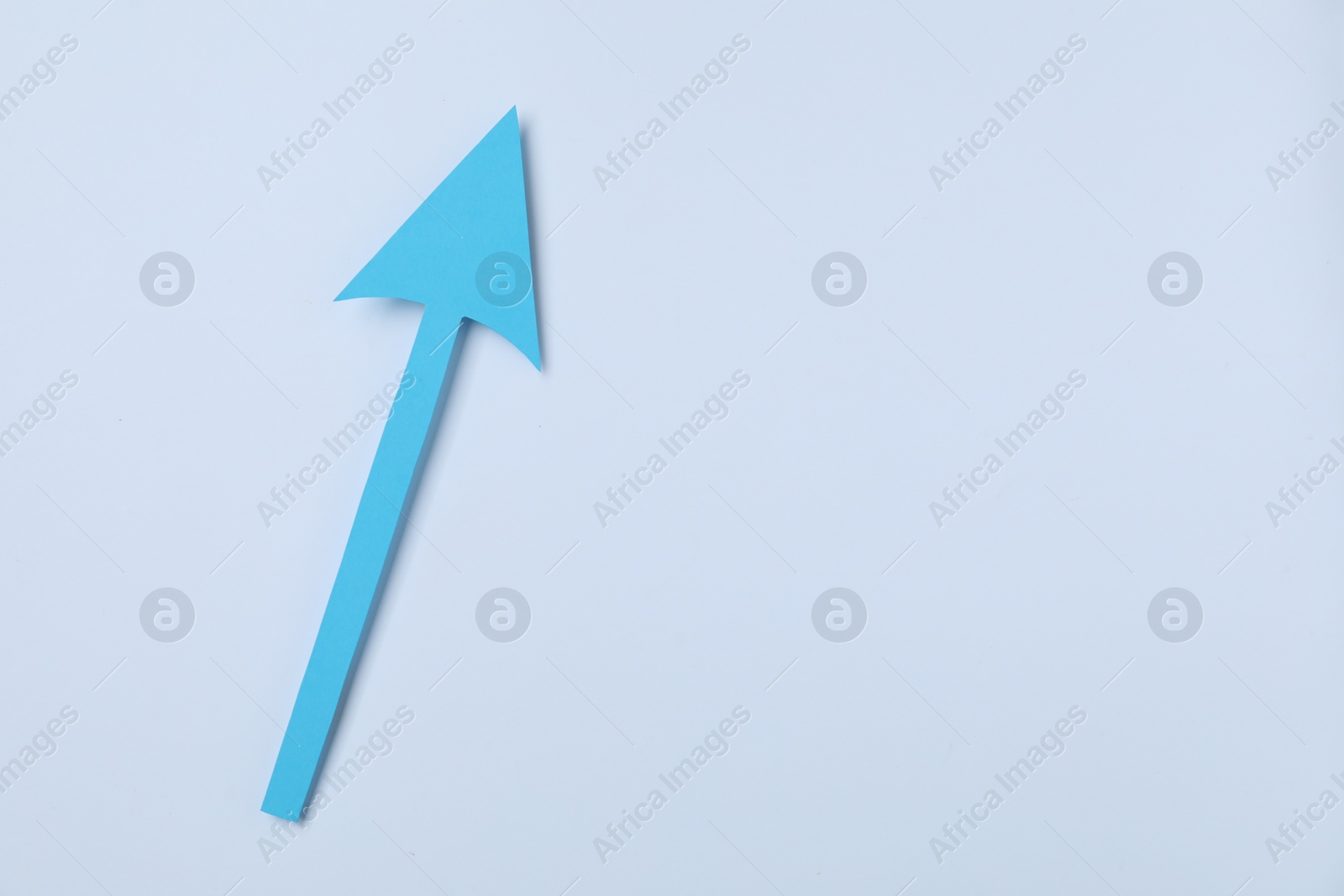 Photo of Light blue paper arrow on white background, top view. Space for text