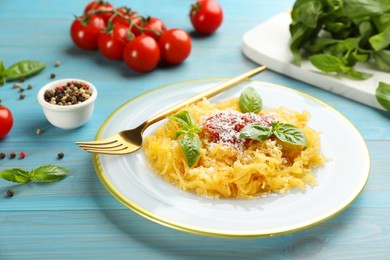 Photo of Tasty spaghetti squash with tomato sauce, cheese and basil served on light blue wooden table