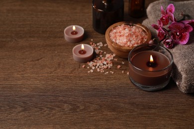 Photo of Beautiful spa composition with burning candles, sea salt and flowers on wooden table. Space for text
