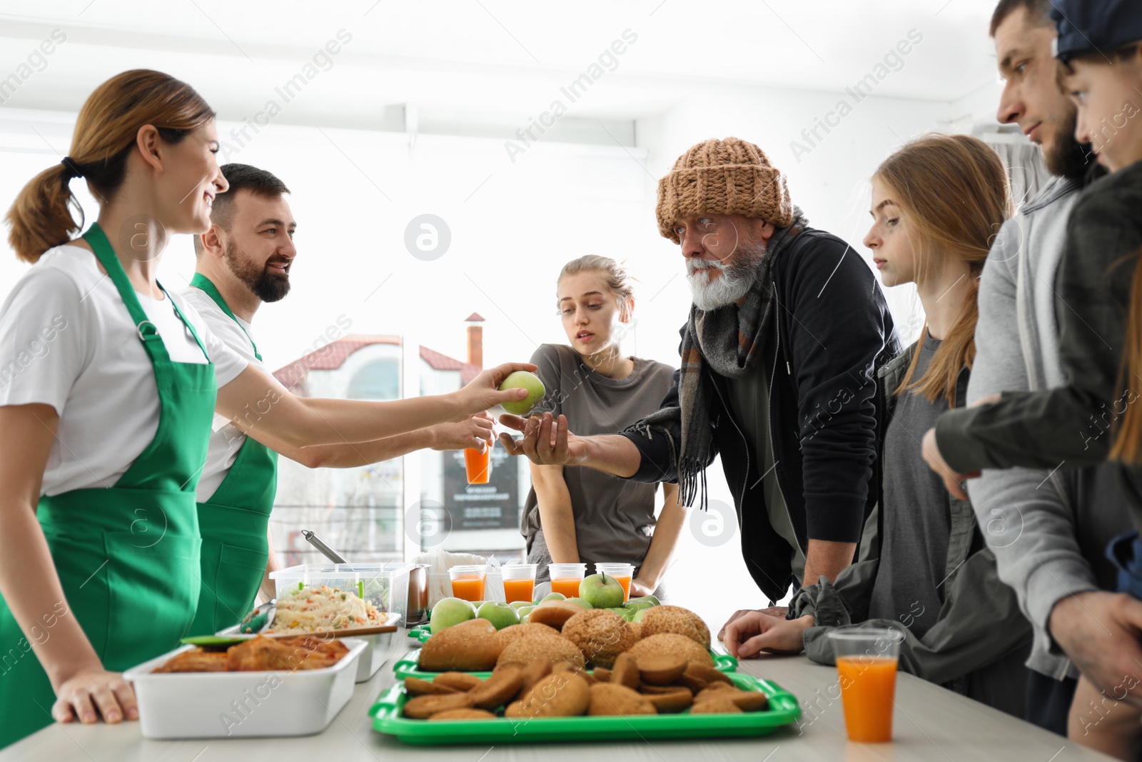 Photo of Poor people receiving food from volunteers indoors