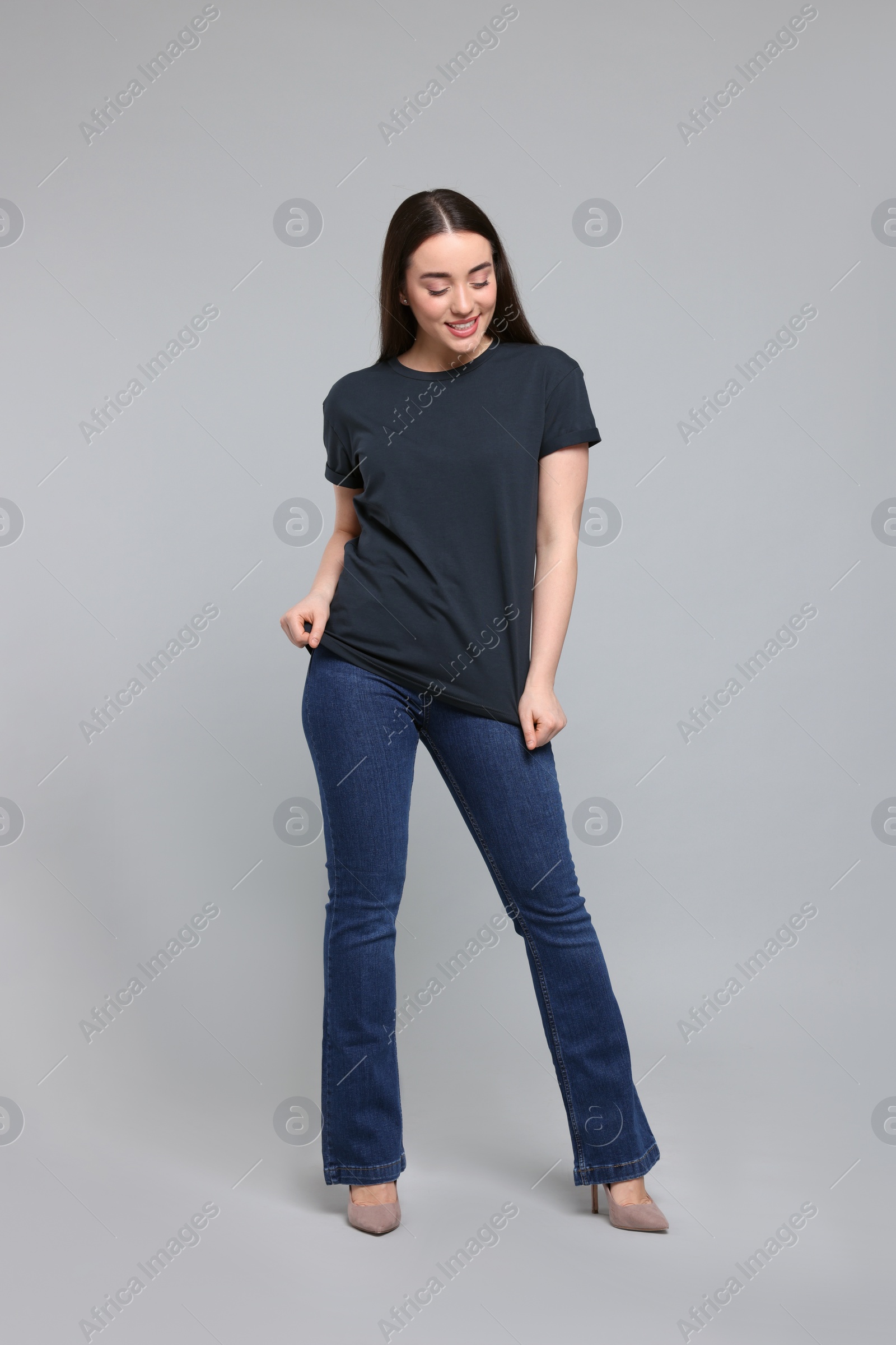 Photo of Young woman in stylish jeans on grey background. Space for text