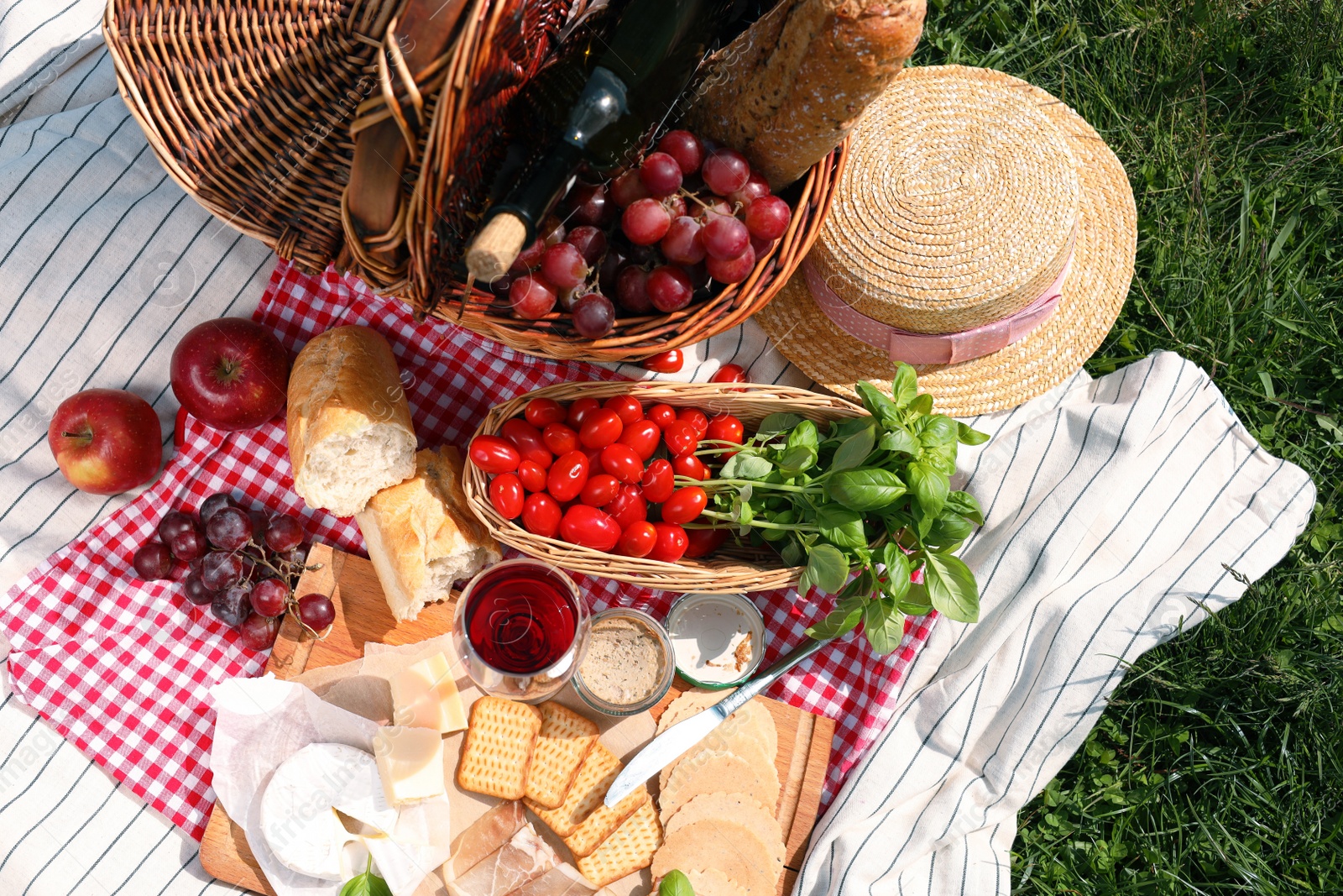 Photo of Blanket with different products on green grass, top view. Summer picnic