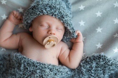 Photo of Cute newborn baby in warm hat sleeping on bed, top view