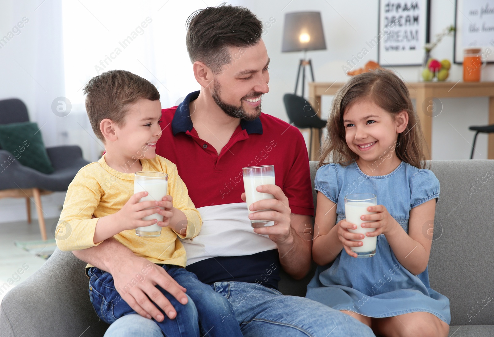 Photo of Happy family with glasses of milk in living room