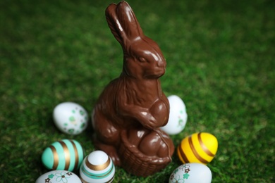 Photo of Chocolate bunny and eggs on green grass. Easter celebration