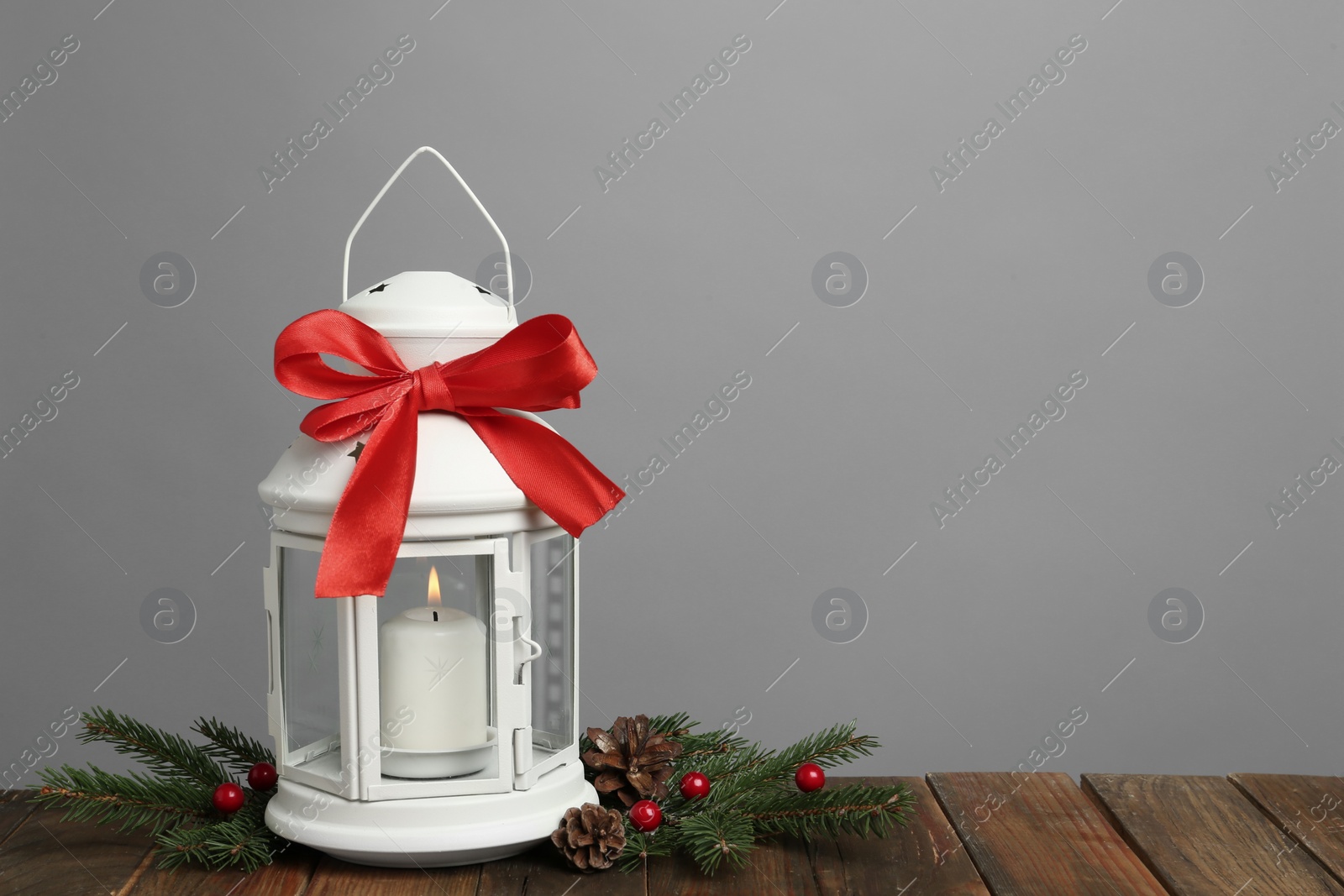 Photo of Decorative Christmas lantern with bow and coniferous twigs on grey background. Space for text