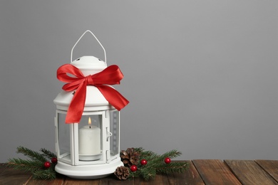 Photo of Decorative Christmas lantern with bow and coniferous twigs on grey background. Space for text