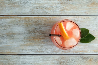 Photo of Glass of grapefruit cocktail on wooden table, top view. Space for text