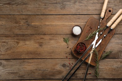 Photo of Flat lay composition with metal skewers on wooden table. Space for text