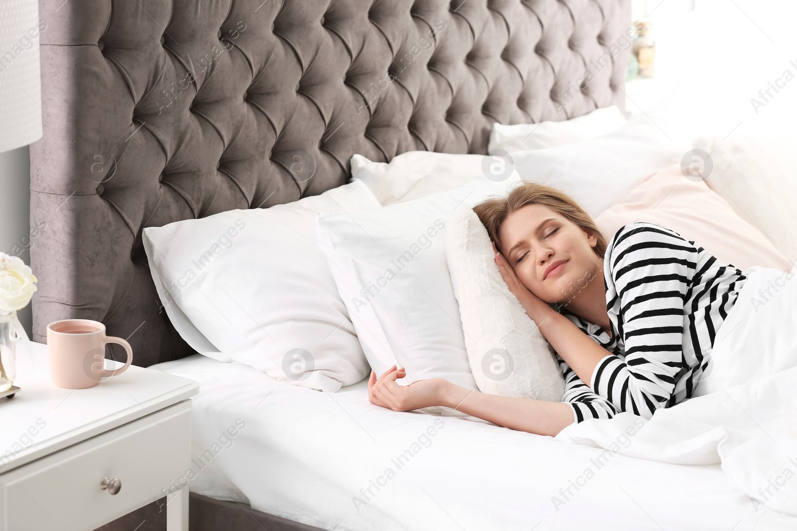 Photo of Young woman sleeping on soft pillows in bed at home