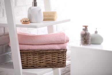 Photo of Basket with clean towels on shelving unit in bathroom. Space for text
